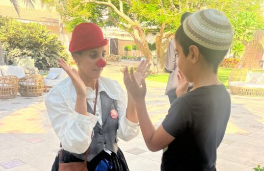 Medical clown Reut Tsoref, also known as Zaza, plays with a boy from Sderot who was evacuated to a hotel near the Dead Sea, in an undated photograph. Courtesy of Dream Doctors